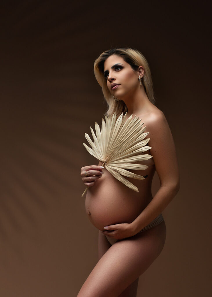Maternity Photography, pregnant woman posing with large palm leaf covering her body